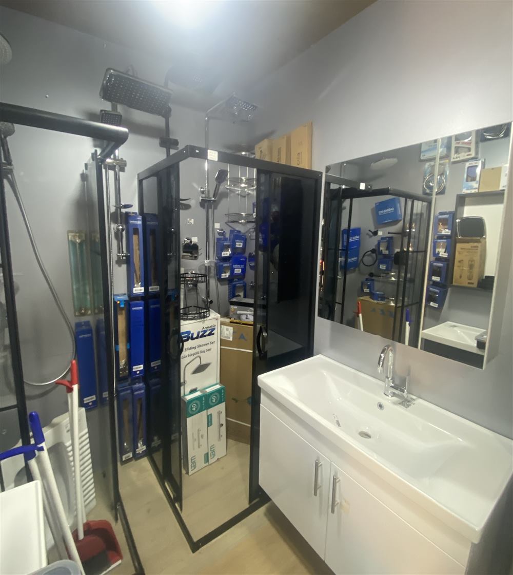 Temsa Yapı Market içinde sergilenen siyah çerçeveli duşakabinler, duş setleri ve lavabolu banyo dolabı