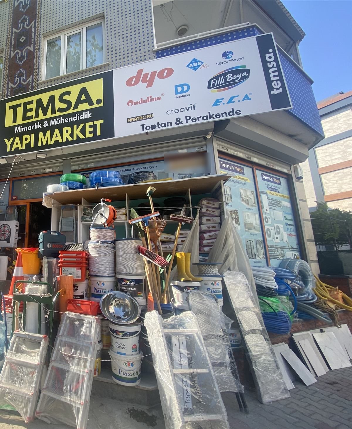 Temsa Yapı Market mağaza cephesi, Millet Caddesi No:58, Soğanlık: tabela, önde boya kovaları, merdivenler ve tesisat boruları